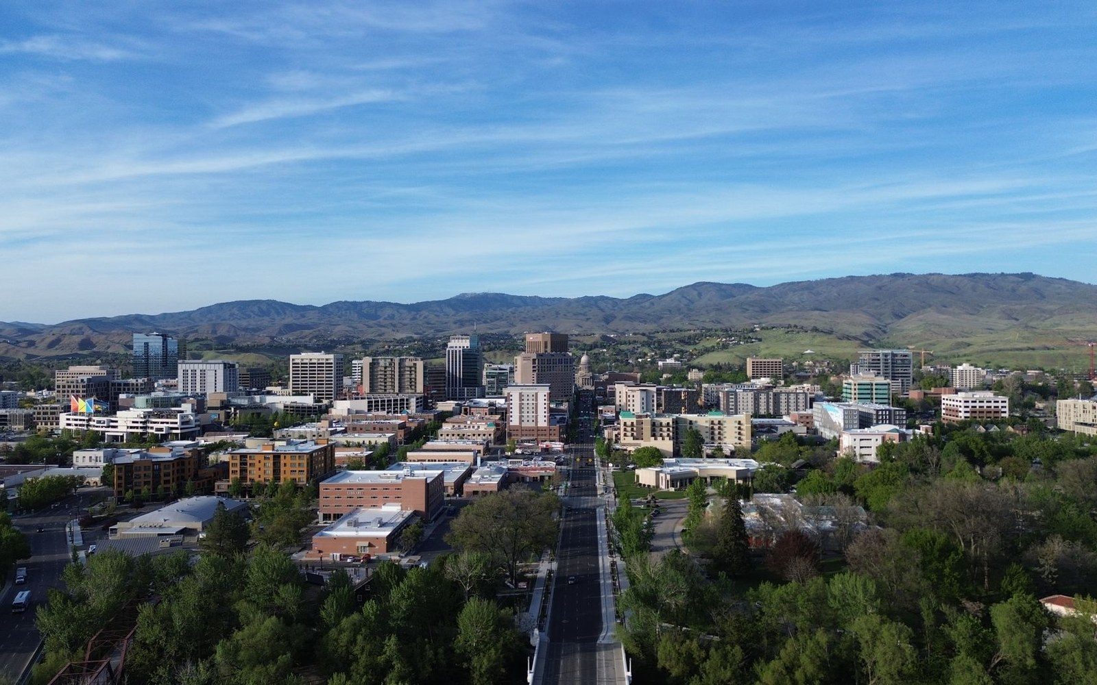Aerial view of a downtown skyline with tree-lined streets and hills in the background