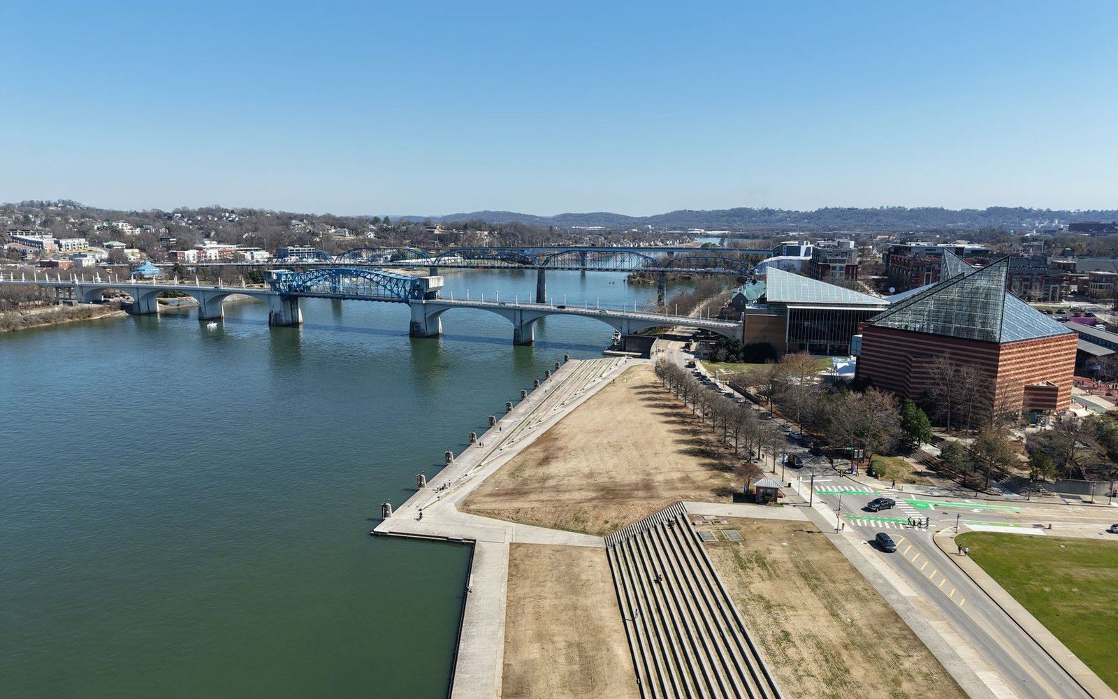 Aerial view of a riverfront park, bridges and aquarium building along the Tennessee River
