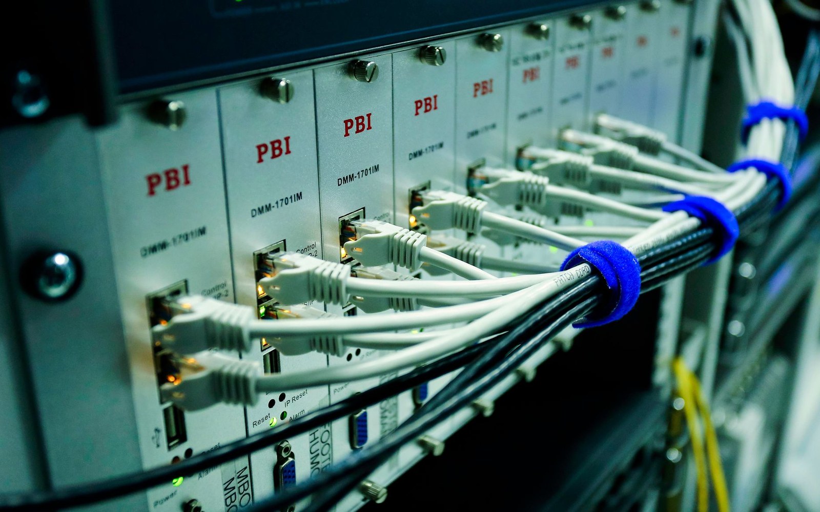 Ethernet cables bundled with blue ties connect to a rack of network equipment modules