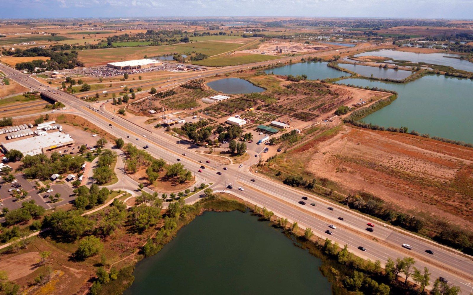 Aerial view of a highway crossing ponds and farmland near a small town