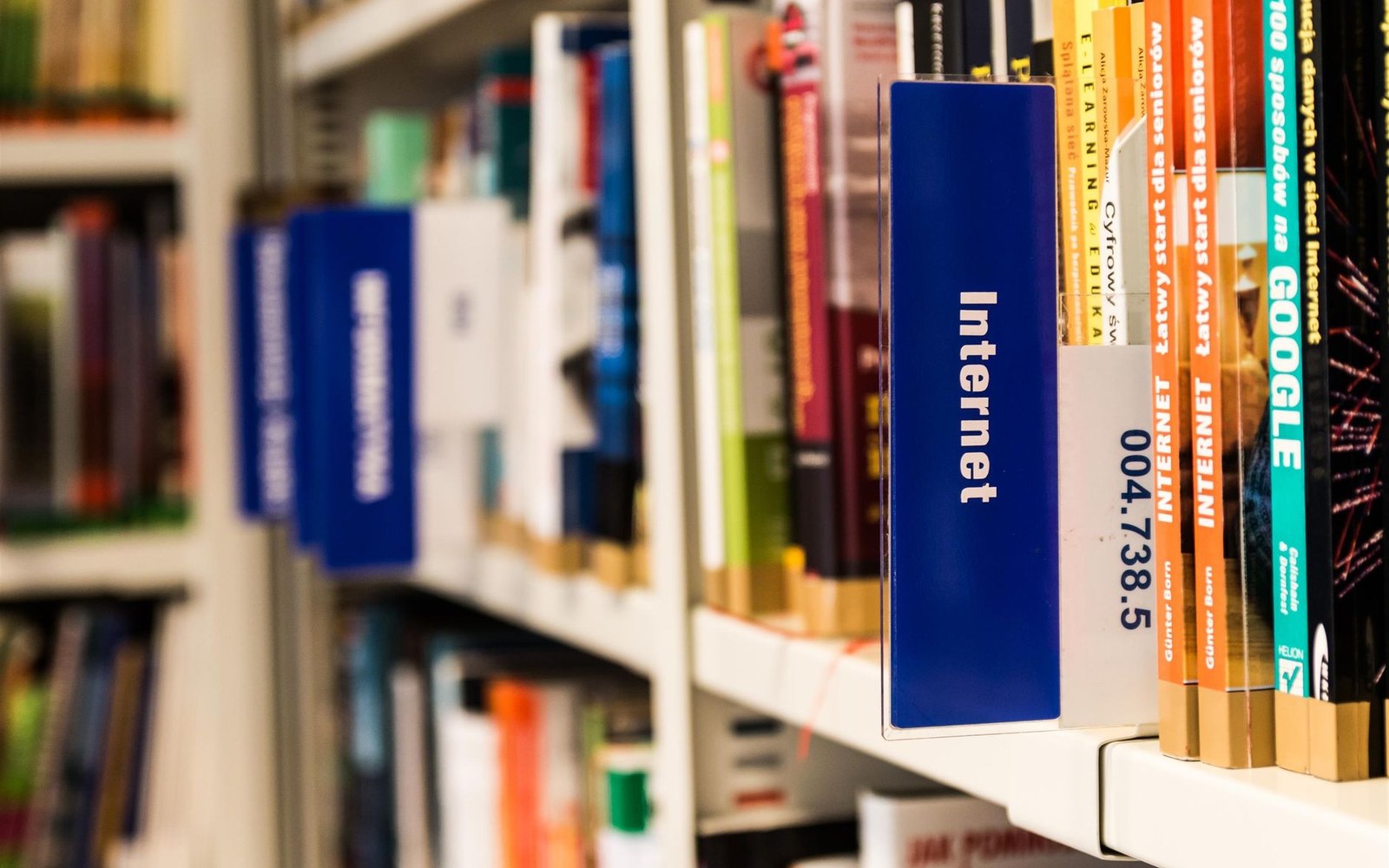 Library shelving with a section label reading Internet, books on public computing beside it